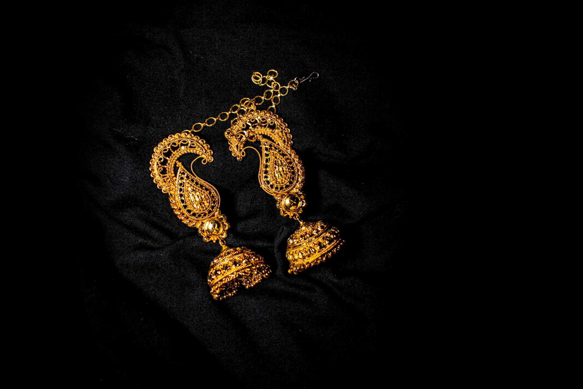 Ornate gold drop earrings on black velvet