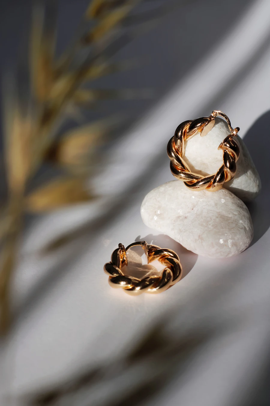 Twisted gold hoop earrings resting on white stones