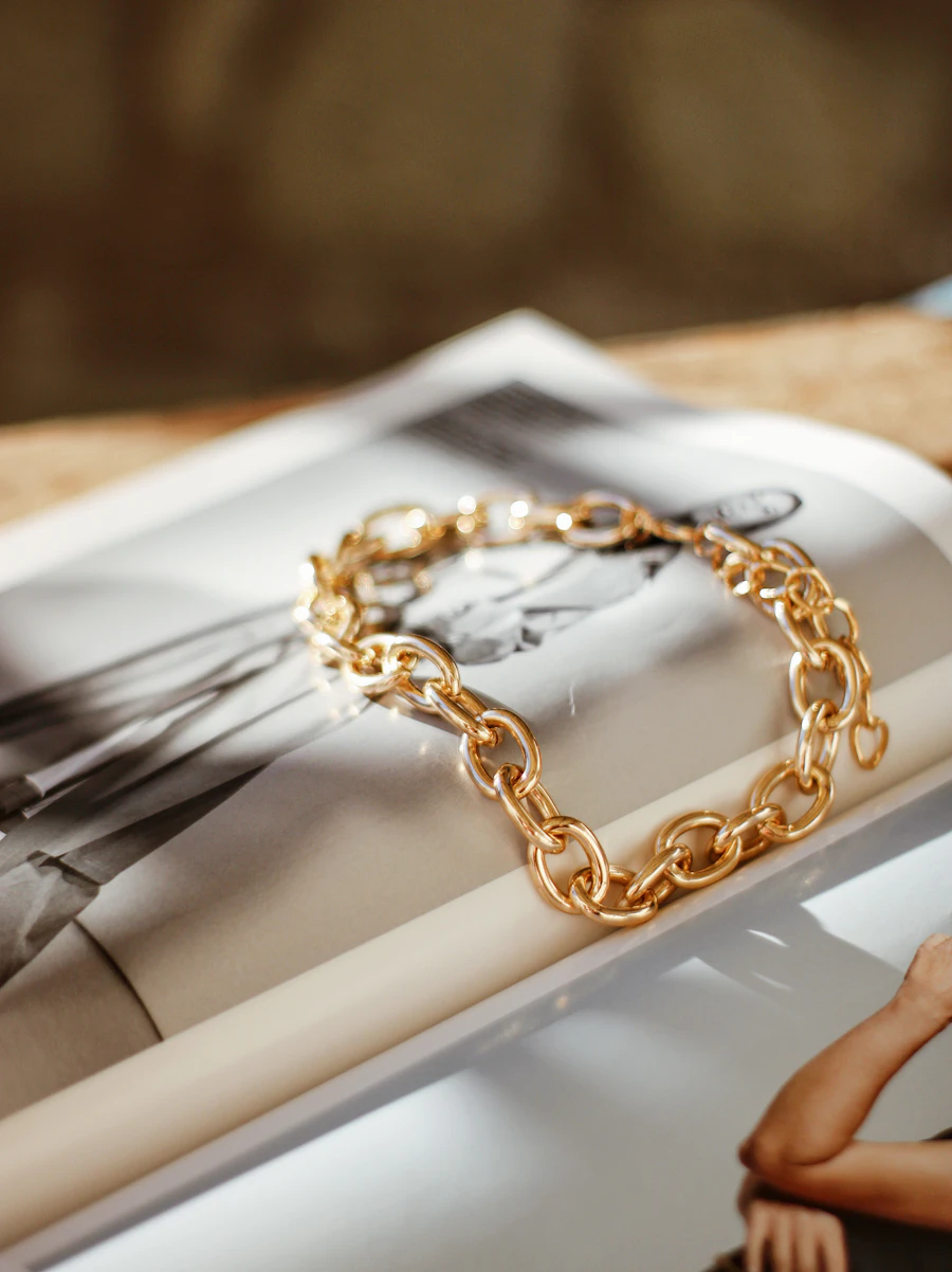 Gold rolo link bracelet on an open magazine